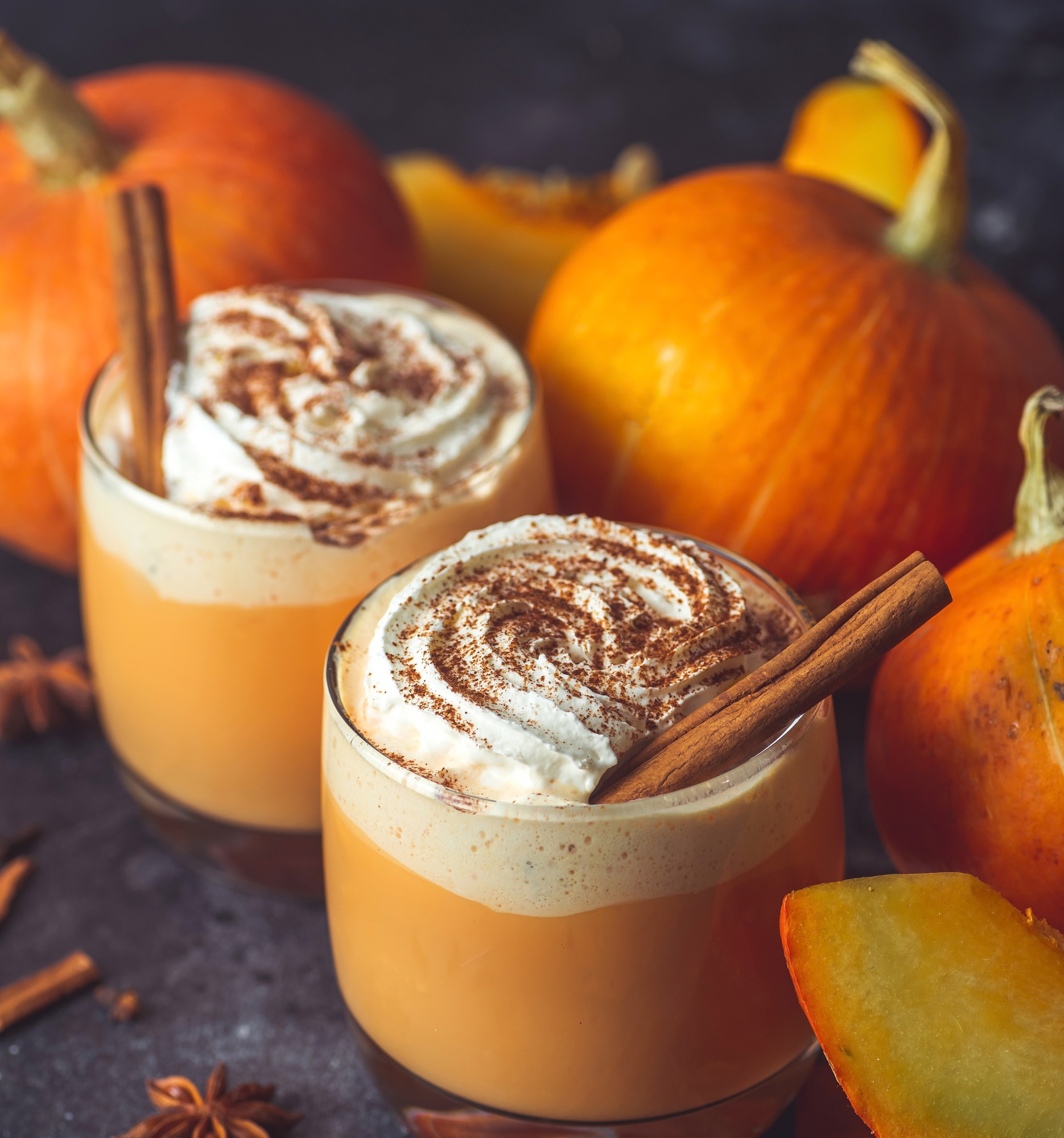 Latte à la citrouille épicée garni de crème fouettée, entouré de citrouilles